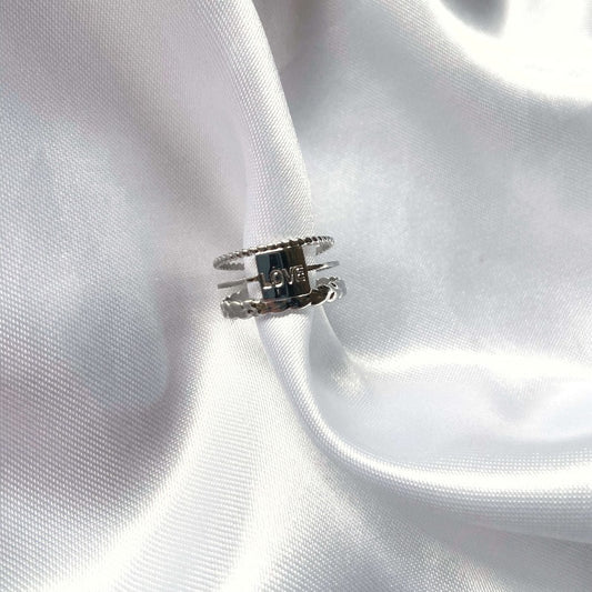 La bague d'amour par excellence, moderne avec ses 3 rangs et explicite avec son message "love" elle sera parfaite comme bague d'amitié, d'union ou comme cadeau à un membre de la famille. Ajustable et en acier inoxydable c'est un bague qui peut être offerte à tous sans besoin de connaitre sa taille, et qui durera dans le temps sans rouiller ni ternir.